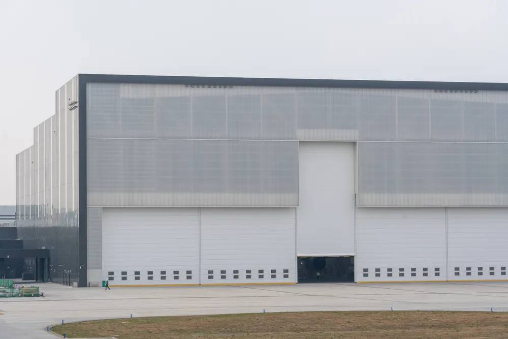 Large modern industrial warehouse exterior with a row of closed bay doors