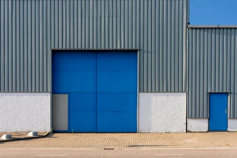 Large blue industrial door on a steel-clad warehouse facade